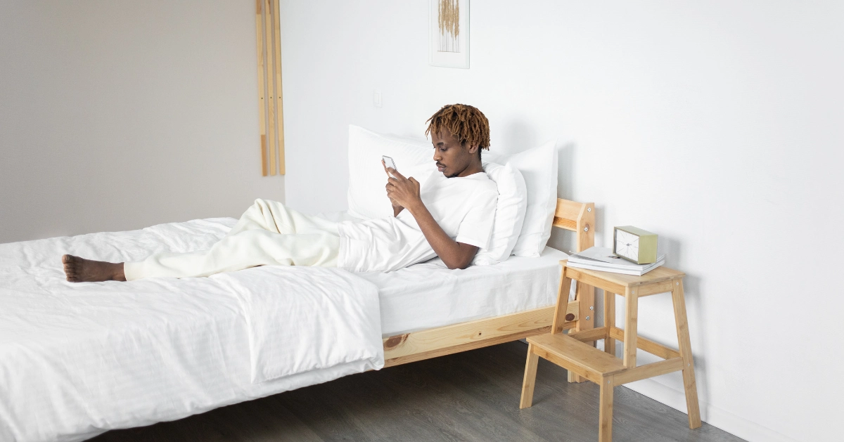 A guy in bed looking at his cell phone