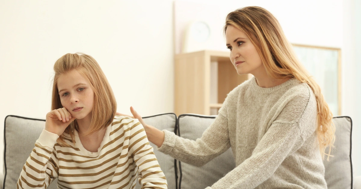 A teen sitting on the couch with her mom
