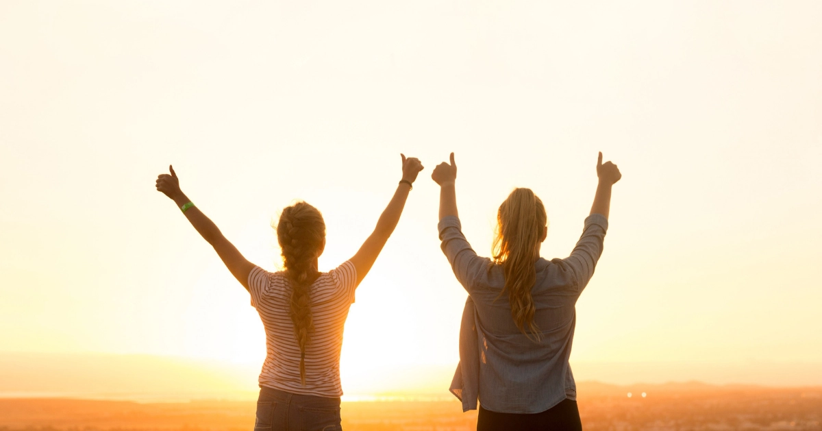 2 girls with arms in air