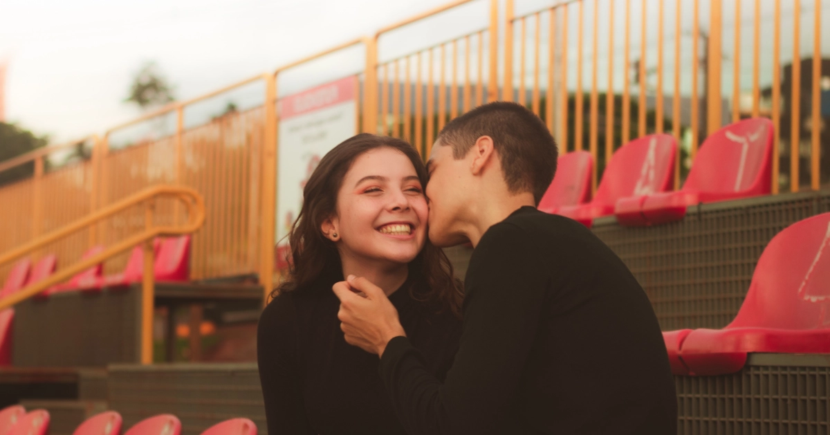 Teen boy kissing a teen girl's cheek.