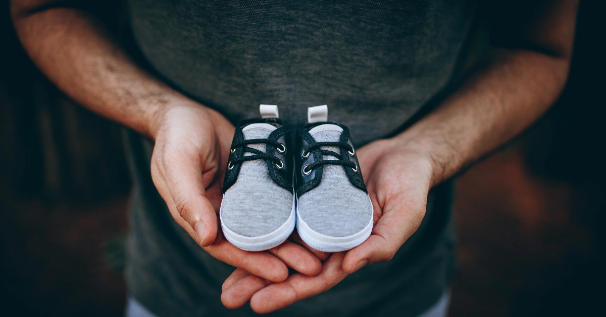 Father holding baby's shoes in his hands.