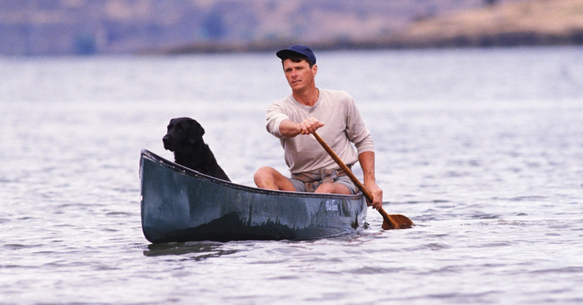 a man and his dog in a canoe