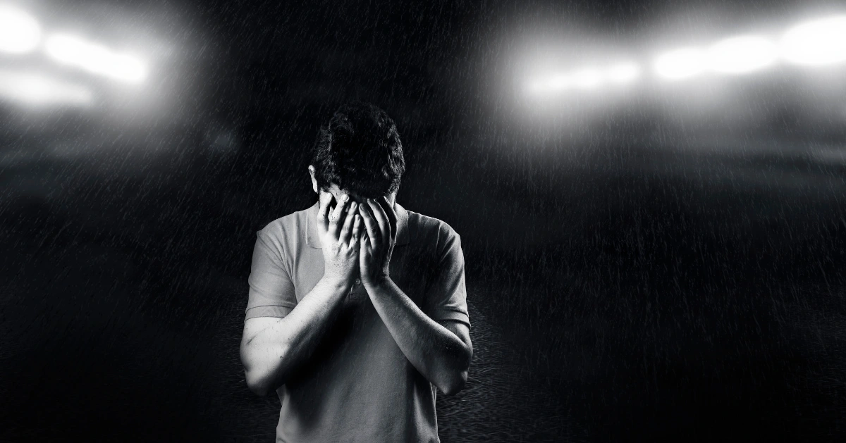 Man hiding his face under bright lights.