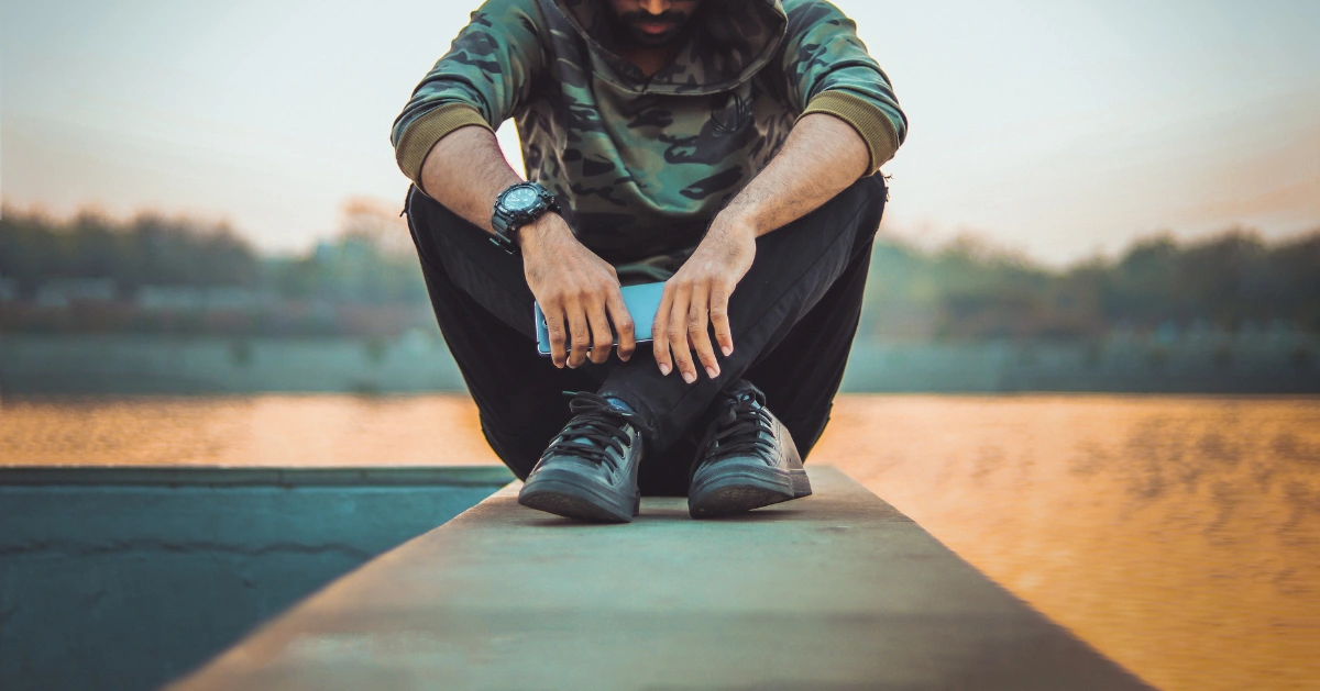 Guy sitting down with his hoodie over his head