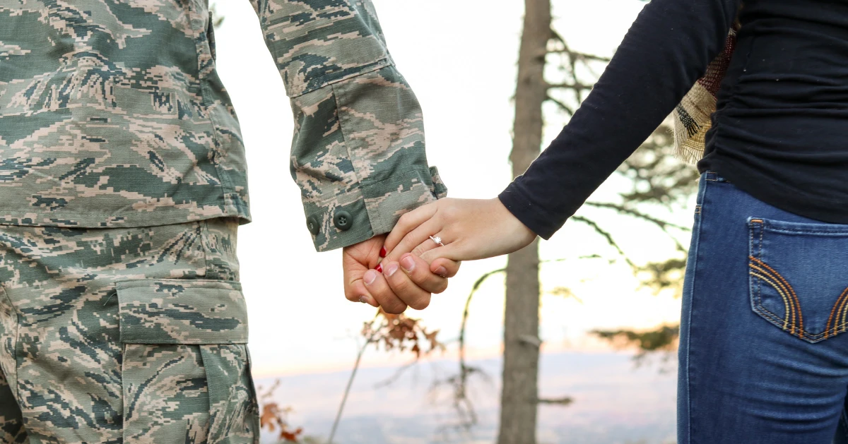 Soliders holding hands with his partner.