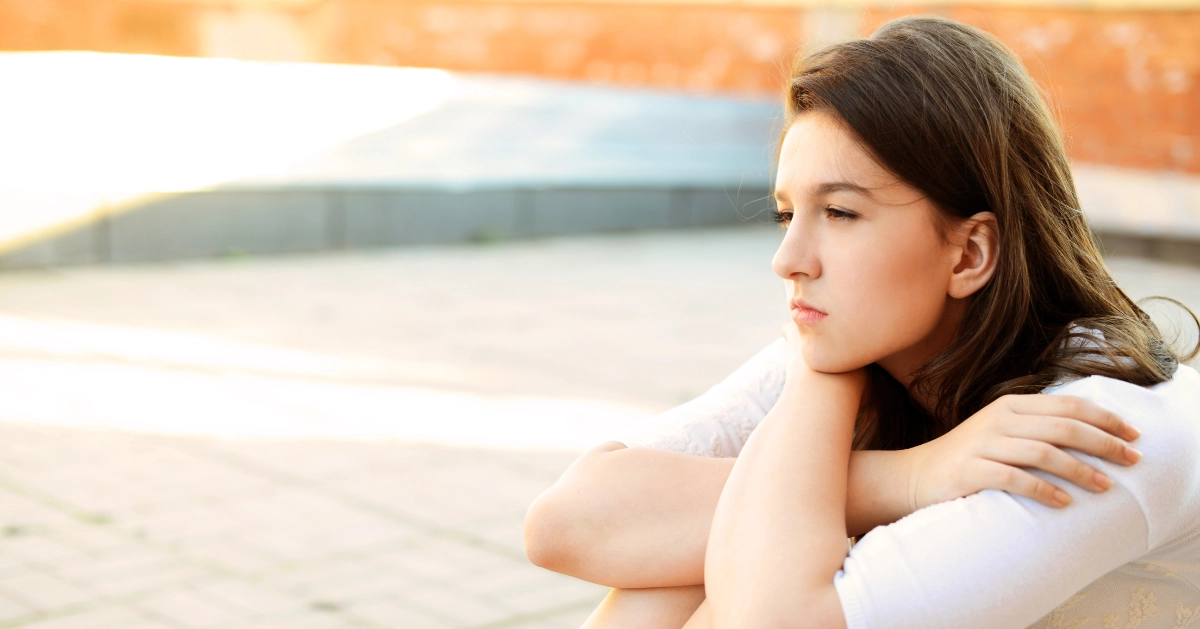 a teen girl sitting down in deep thought