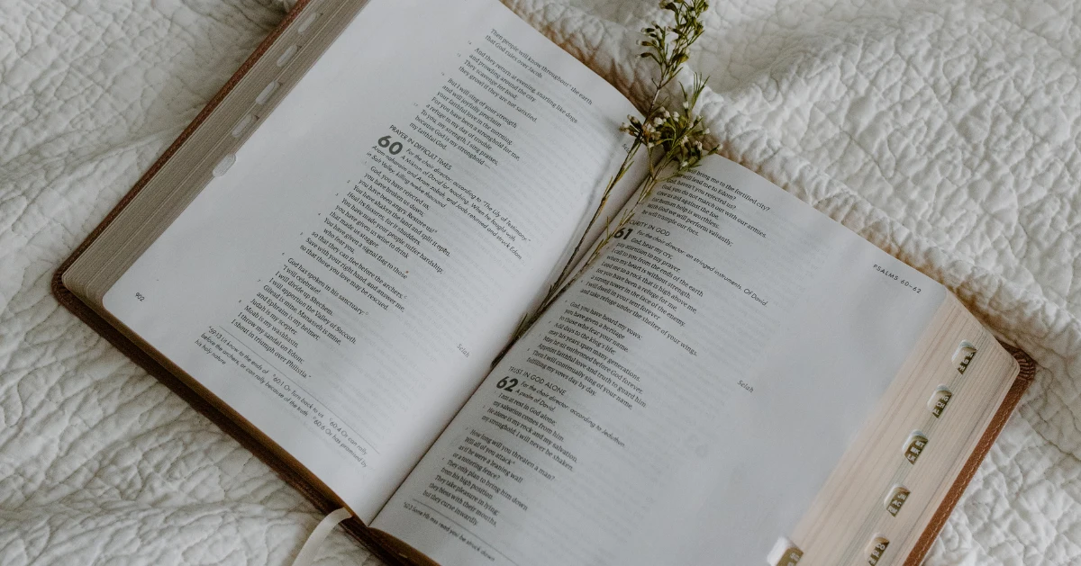 An opened bible on a bed.