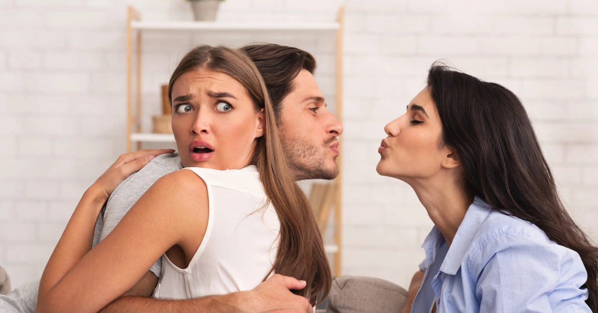 a guy hugging his girlfriend while trying to kiss another girl