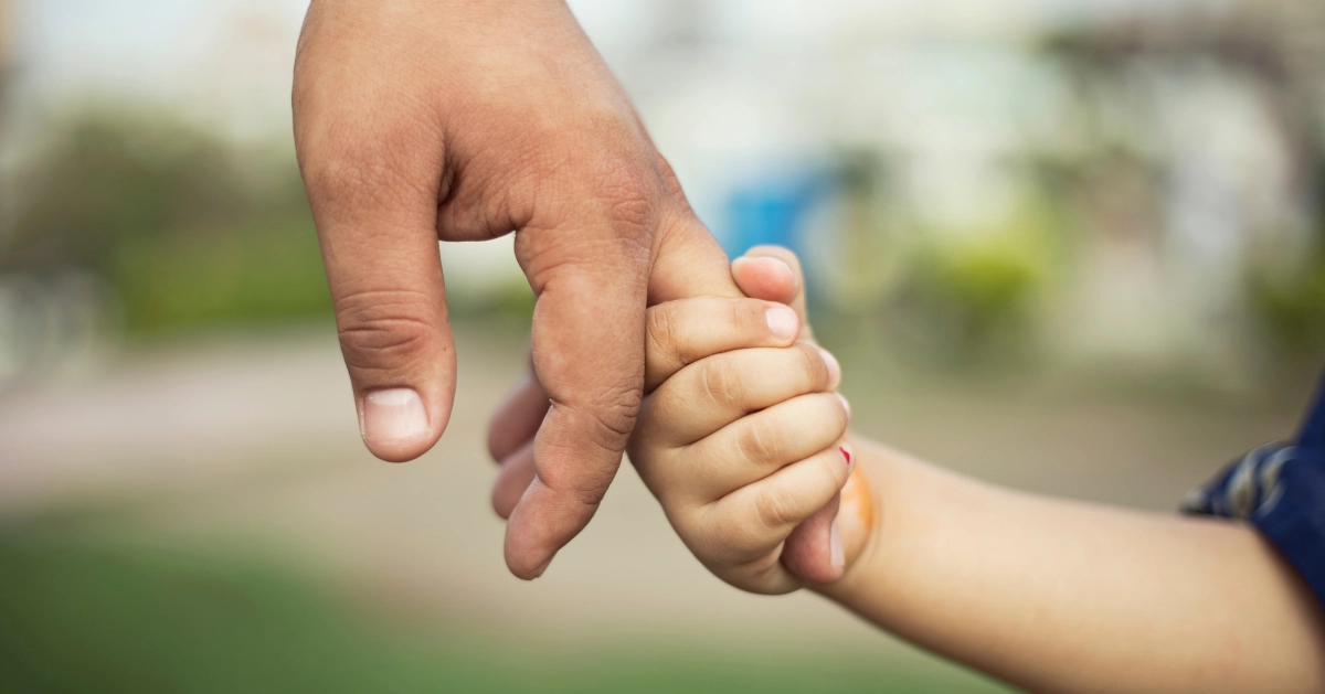 a little girl holding her fathers finger
