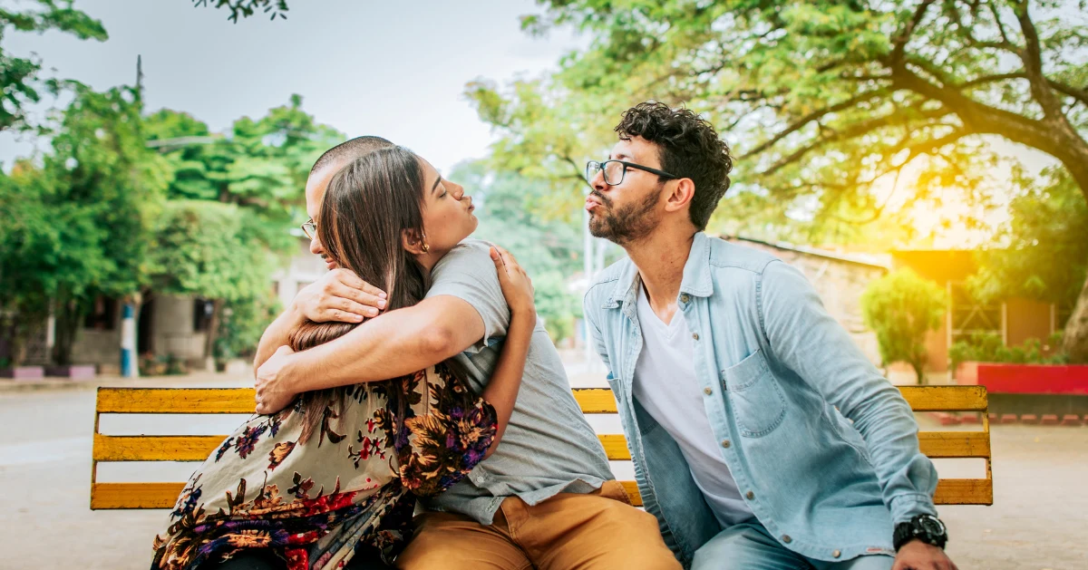 a couple embracing while the girl is blowing a kiss to another guy