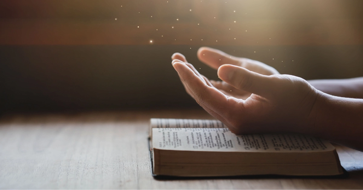 praying hands over a bible