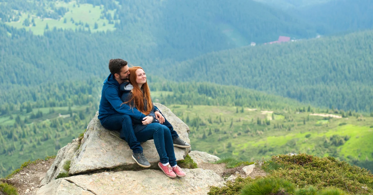 Couple sitting on top of a mountain
