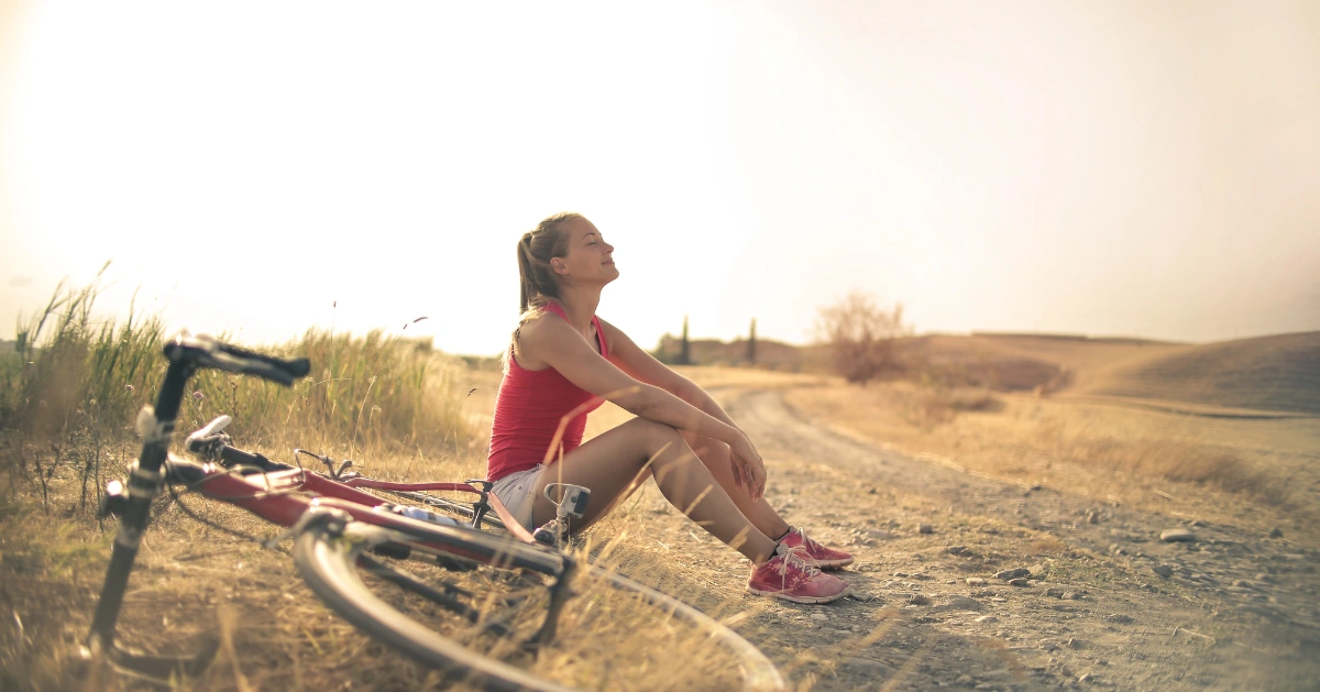 a girl sitting down on the ground with her bicycle
