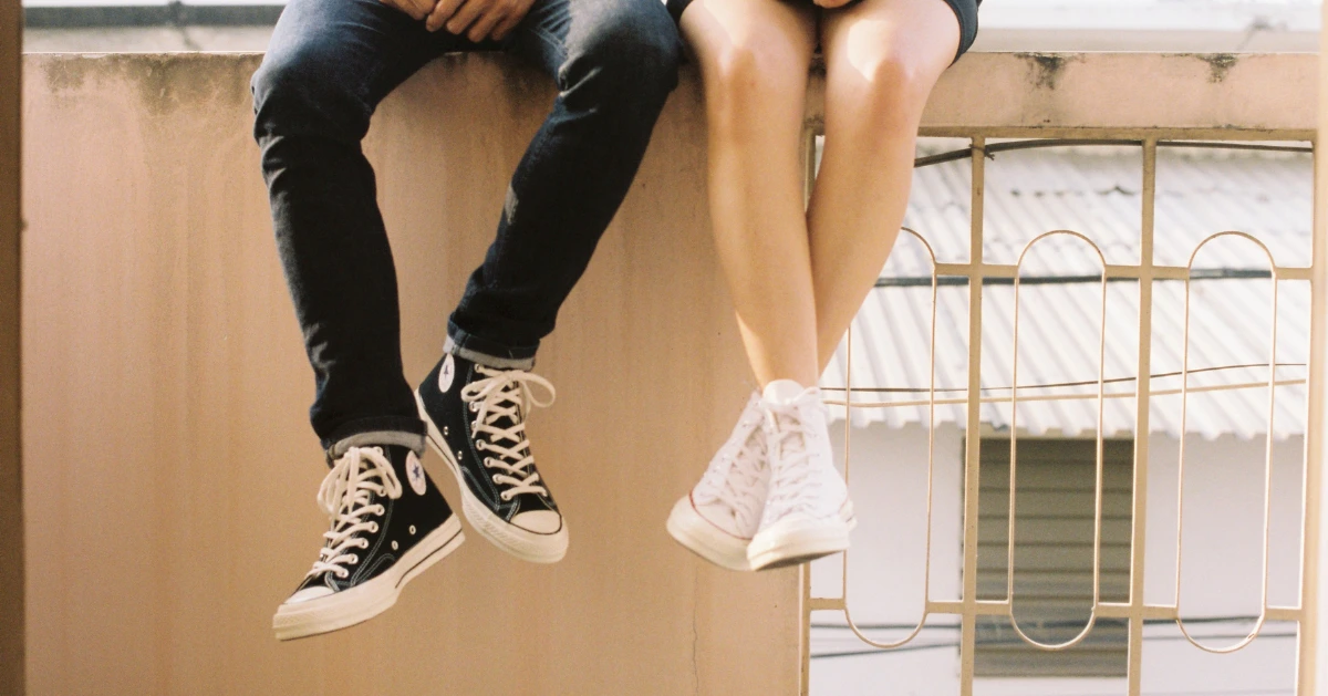 a guy and girl sitting on a brick wall