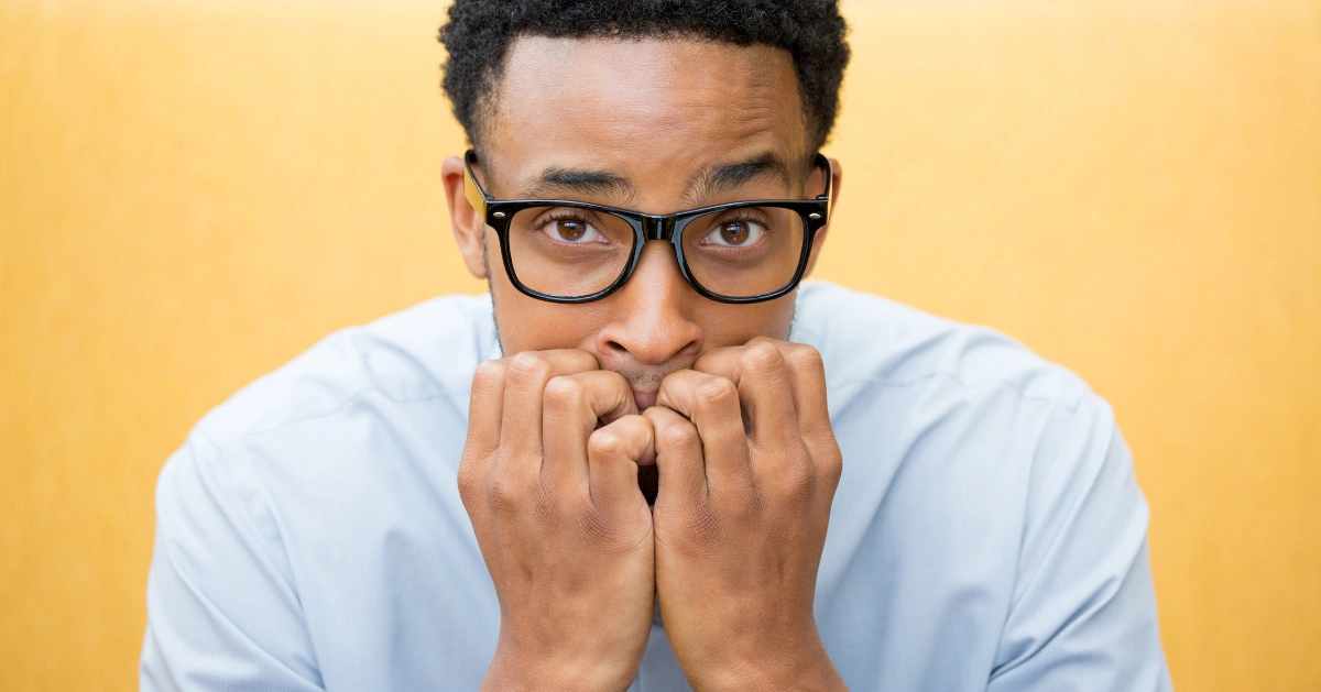 A guy with his fingers in his mouth showing signs of anxiety.