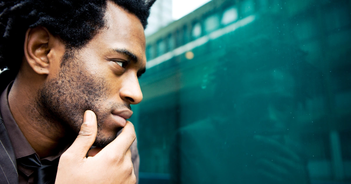A guy on a train looking out the window in deep thought.