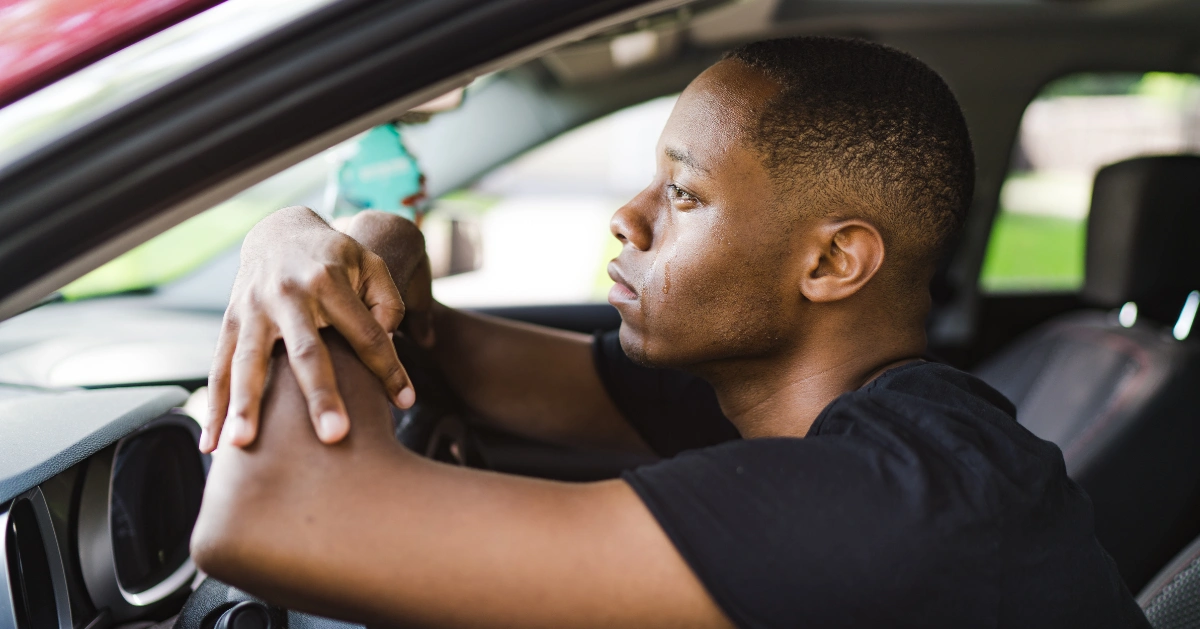 A guy in his car with tears coming down his face.