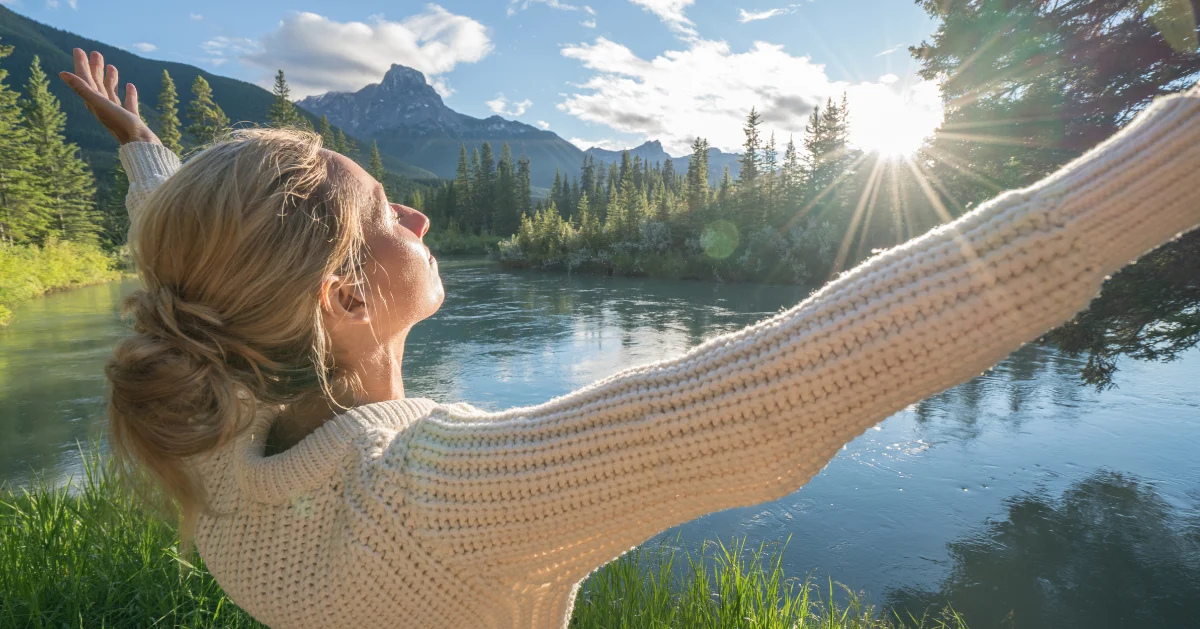 A girl holding out her arms outside to feel at peace.