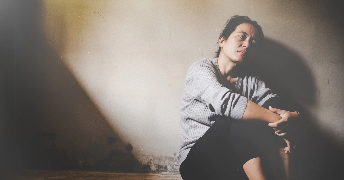 a girl sitting by the window with her head down