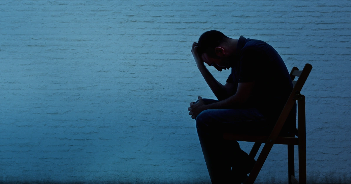 a guy sitting alone in the dark on a chair