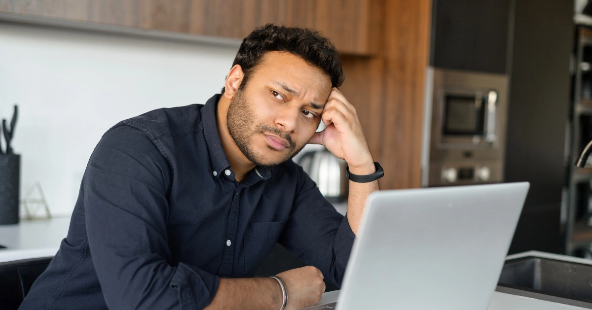 a guy in front of his computer with a worried look on his face
