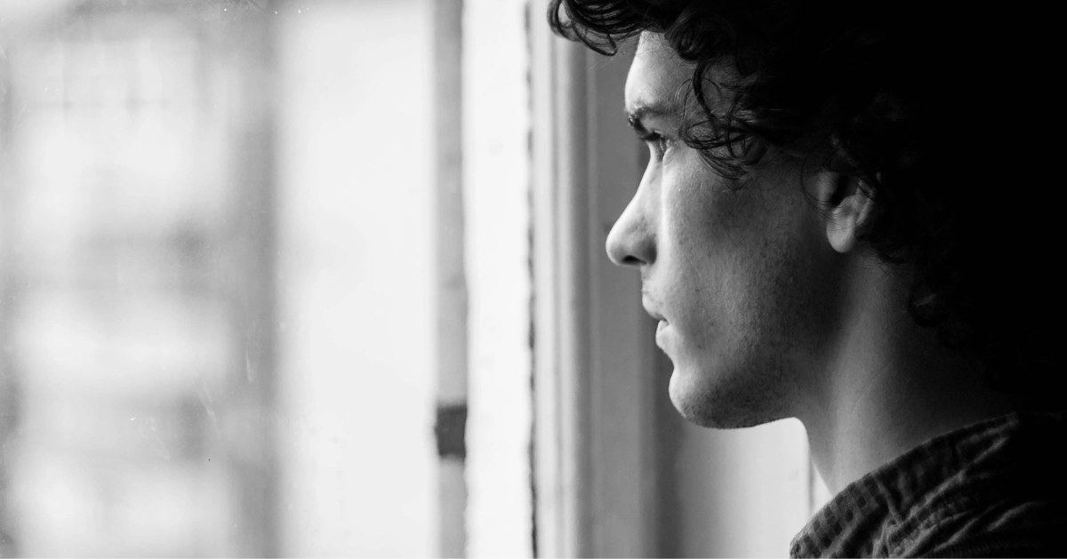a black and white picture of a guy looking out the window
