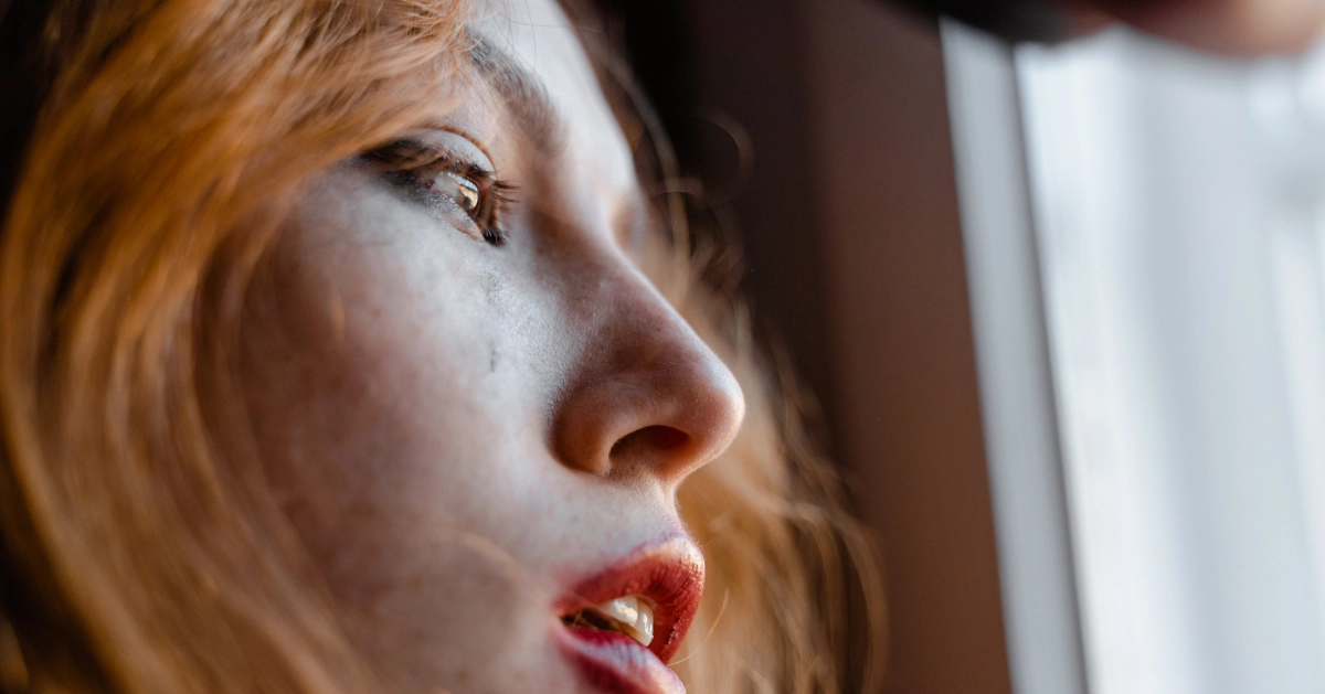 a girl looking out her window with tears running down her cheek