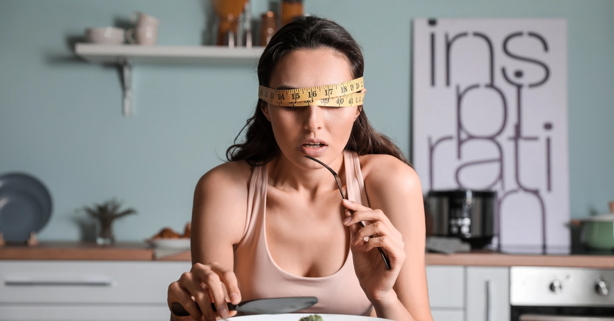 A girl eating being blindfolded with a weight tape over her eyes.