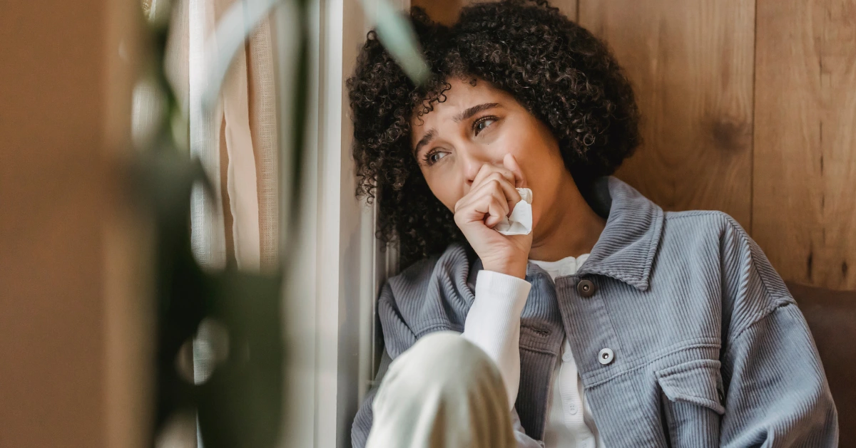 A girl sitting by the window crying