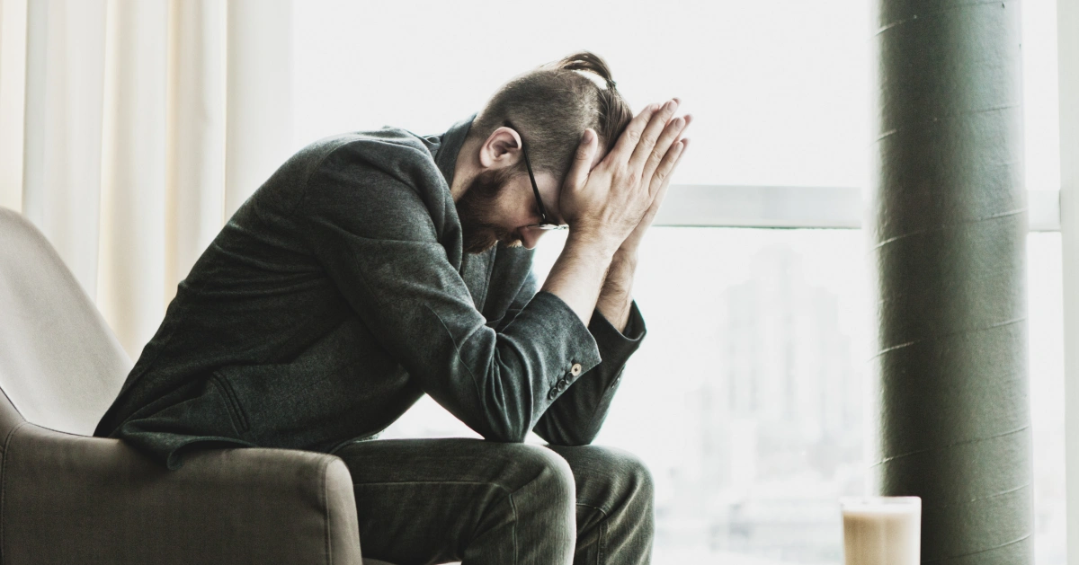 a guy sitting down with his hands around his head