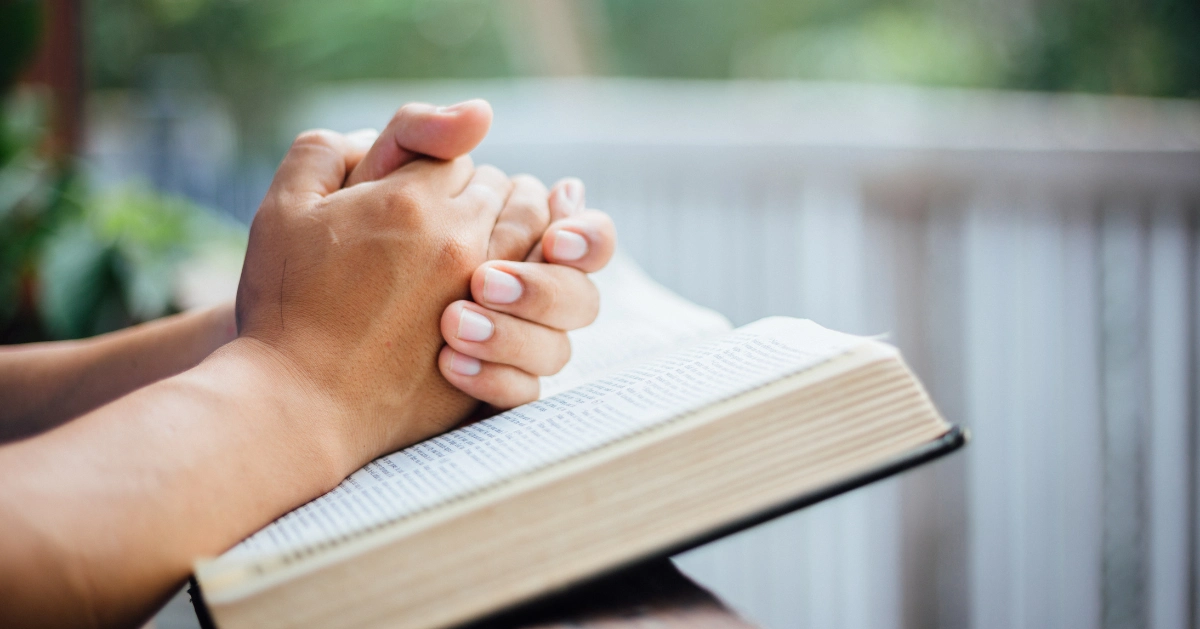 someone praying while the bible lays on their lap