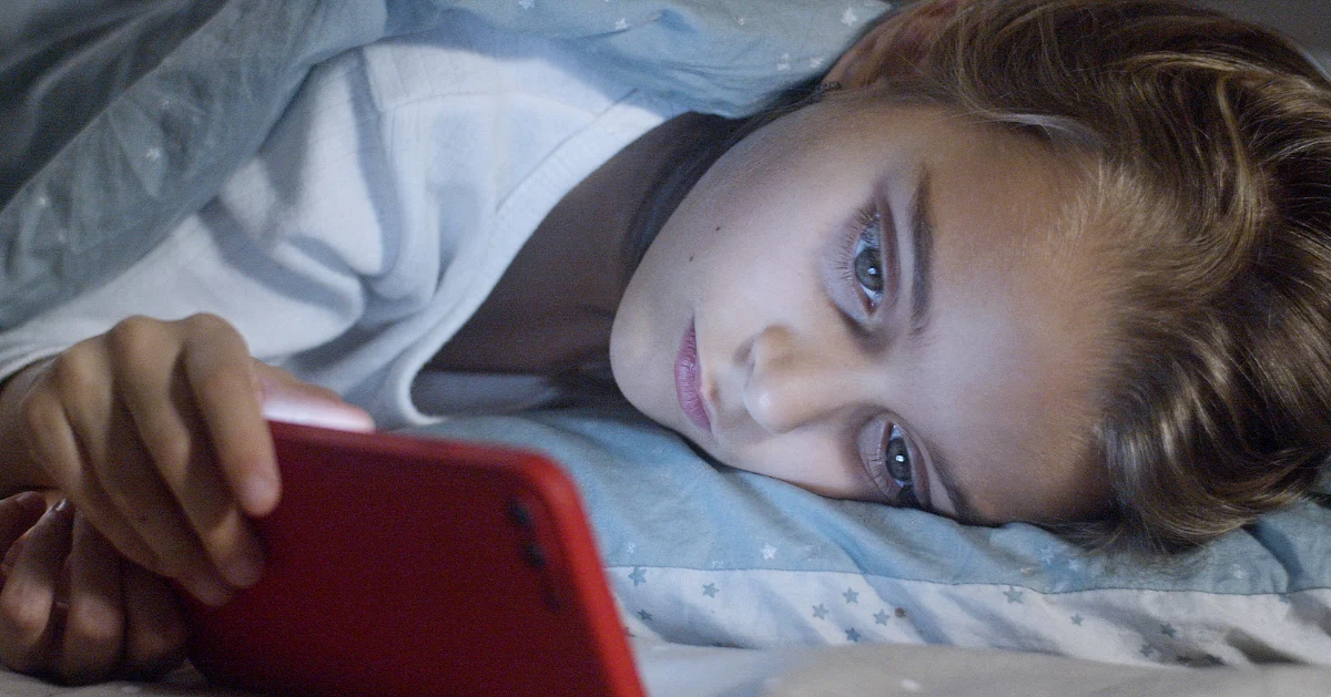 Girl lying in bed looking at her mobile
