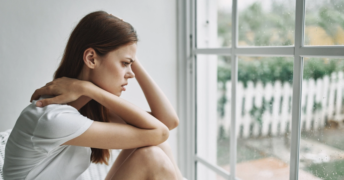 a girl sitting in her room looking scared