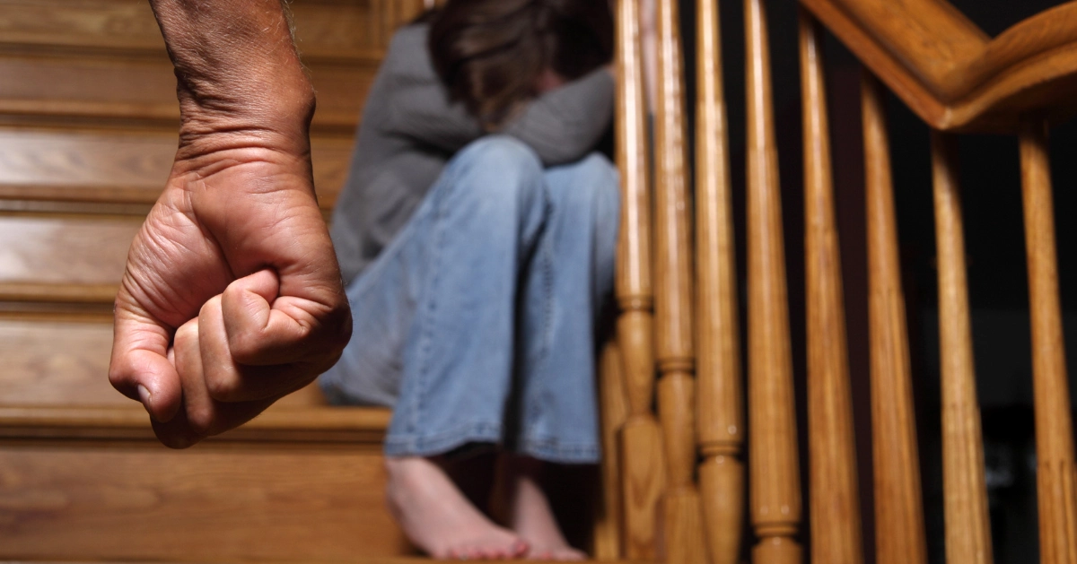 someone sitting on a staircase as a man stands there with his fist tight