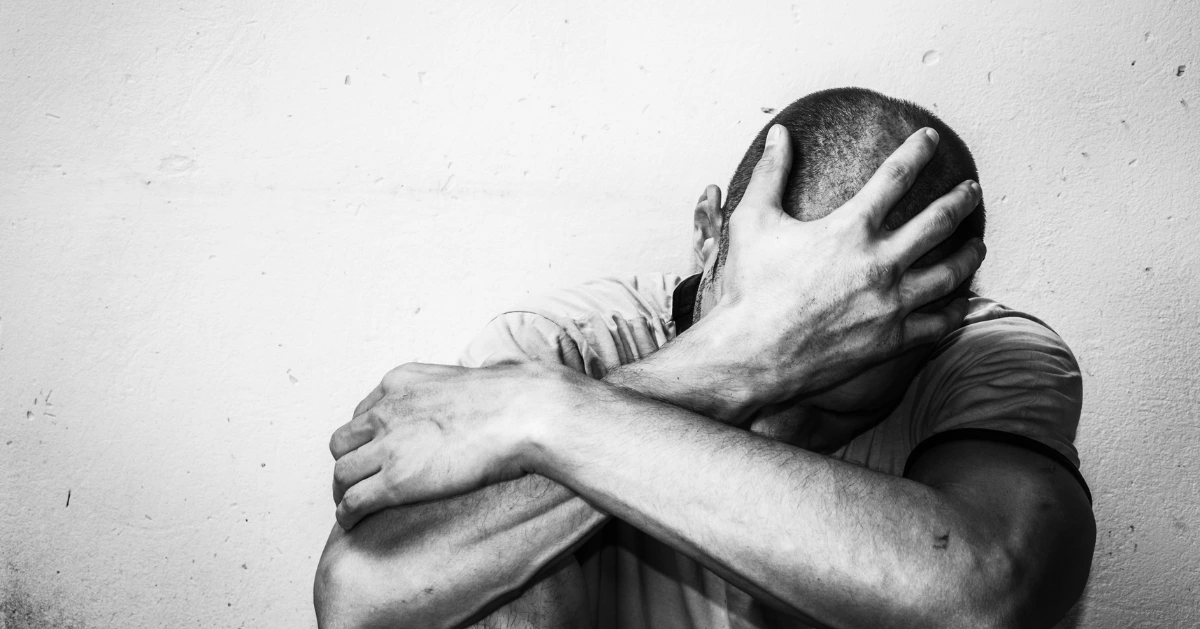 a guy sitting on the floor with his hand on his head