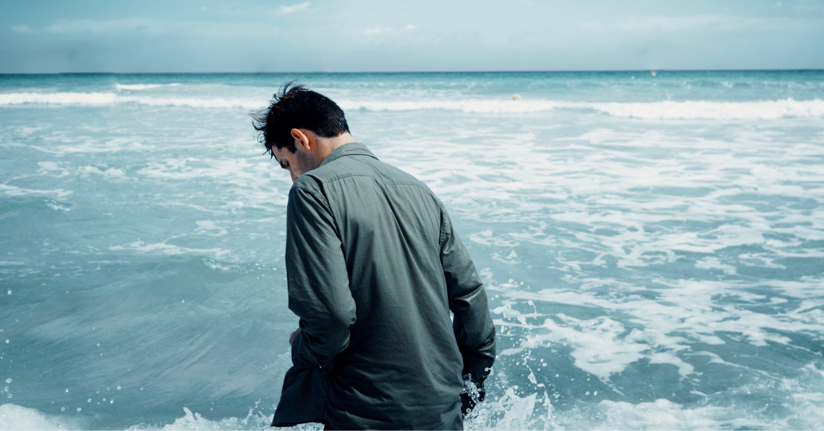 Guy walking in the ocean with his head down
