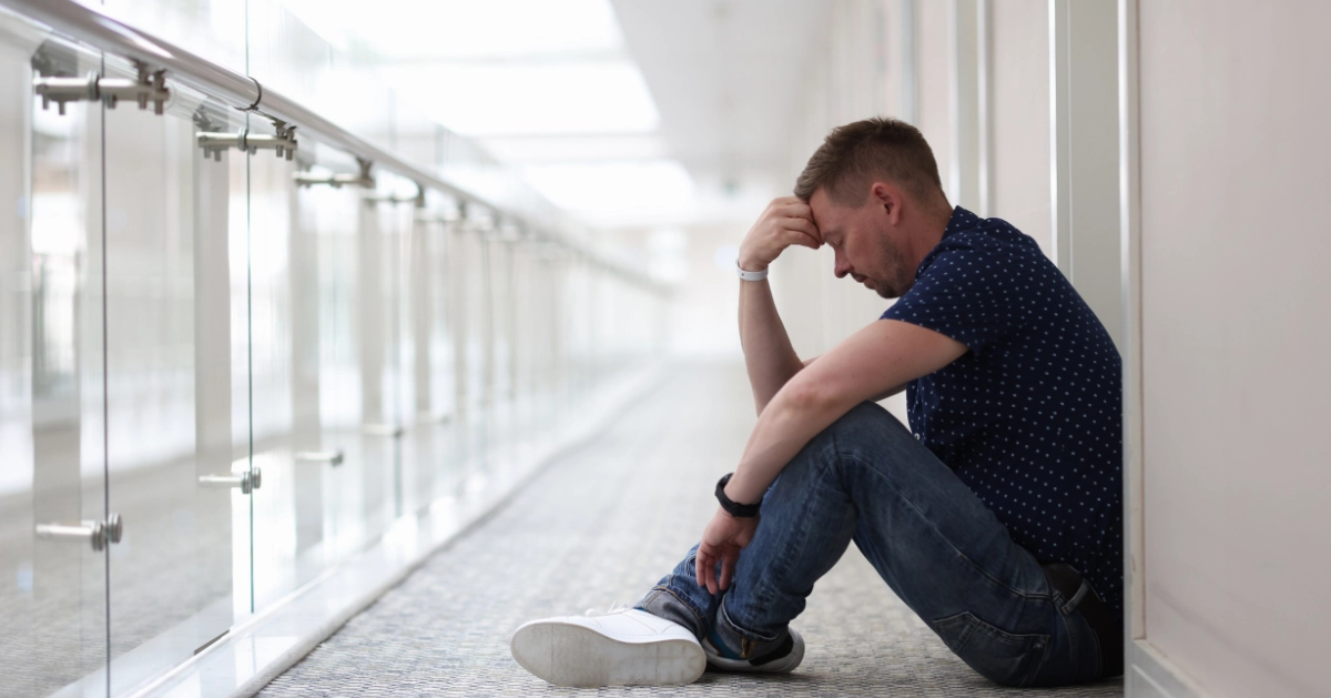 a guy sitting on the floor holding his head