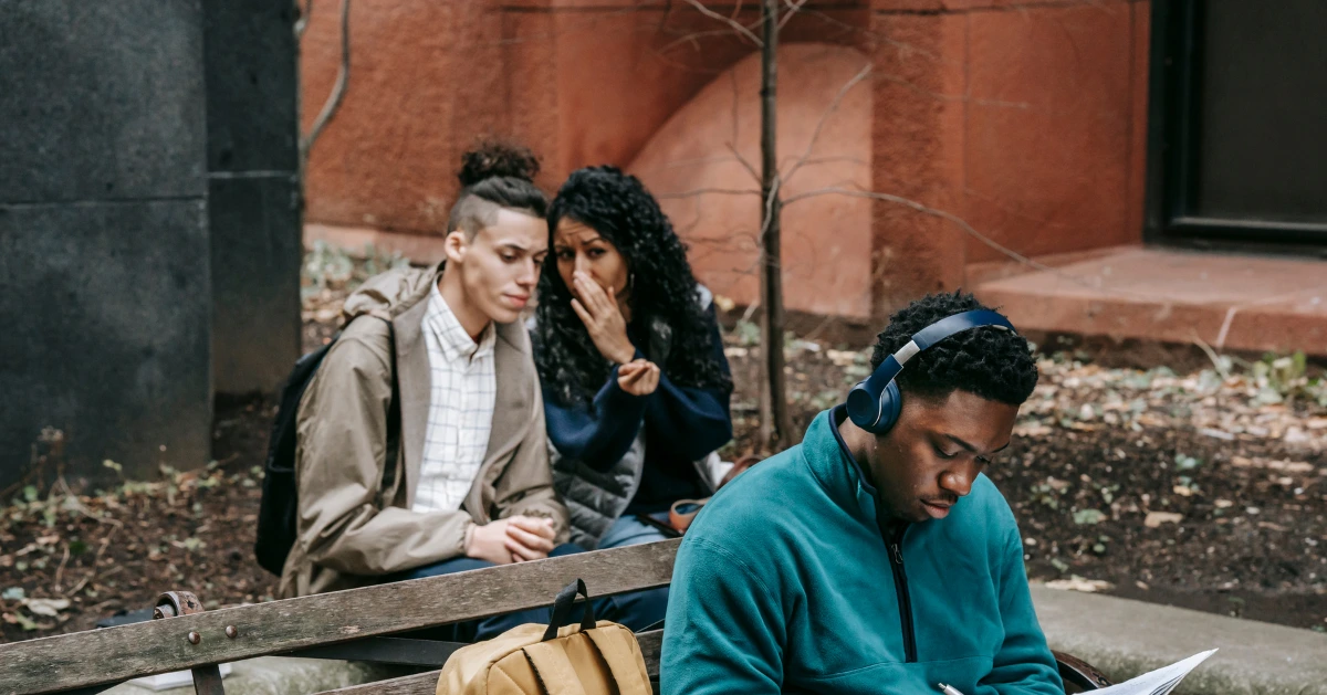 Friends whispering behind a guy.