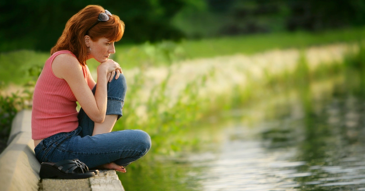 a lady sitting by the lake
