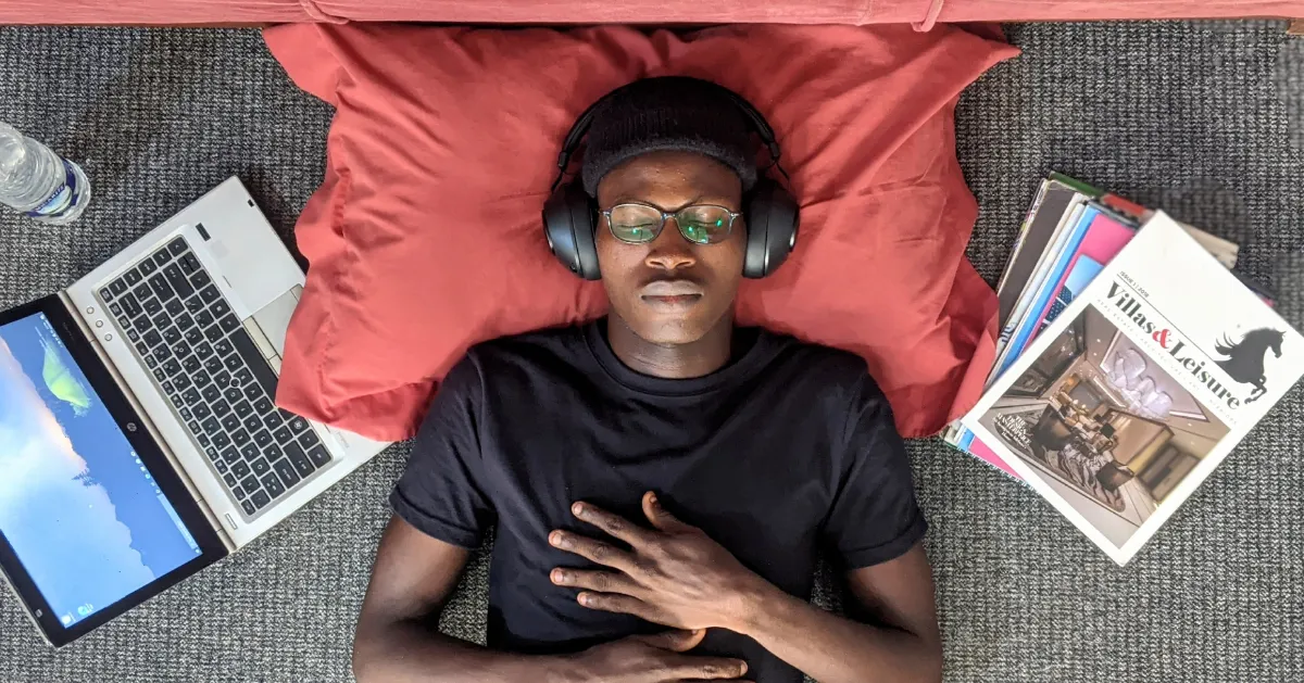 Guy laying down in bed listening to music.