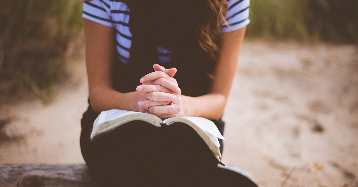 girl with hands on an open bible