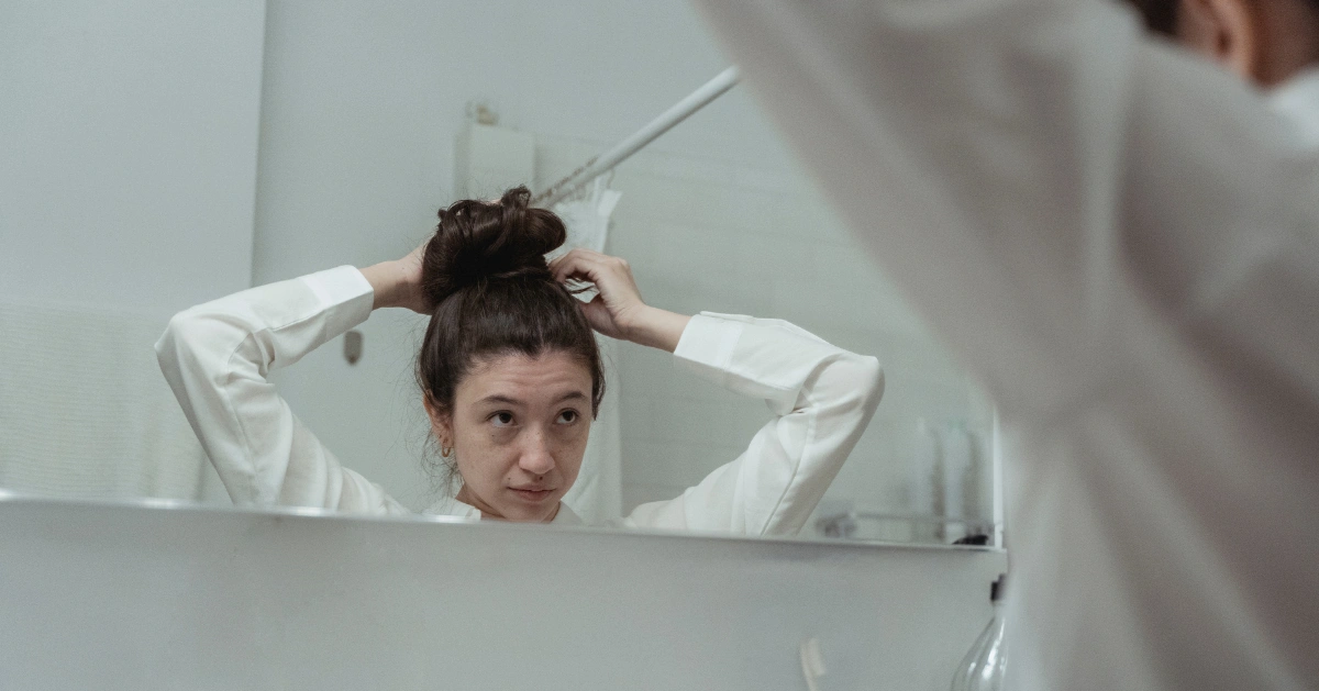 Woman looking in a mirror fixing her hair