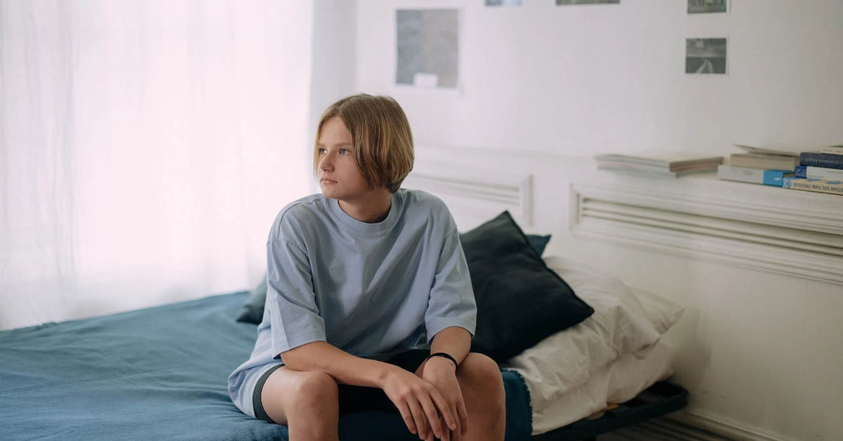teen male sitting alone on his bed